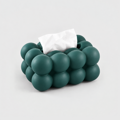 Teal bubble tissue box cover in matte ceramic with a tissue in its top slot, on a light gray background