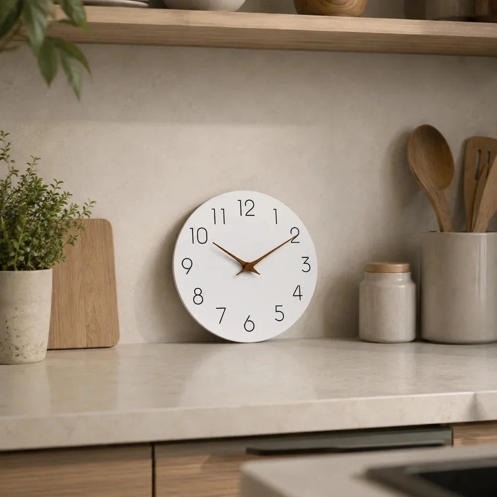 The white clock with wooden hands standing on a kitchen counter against the backsplash