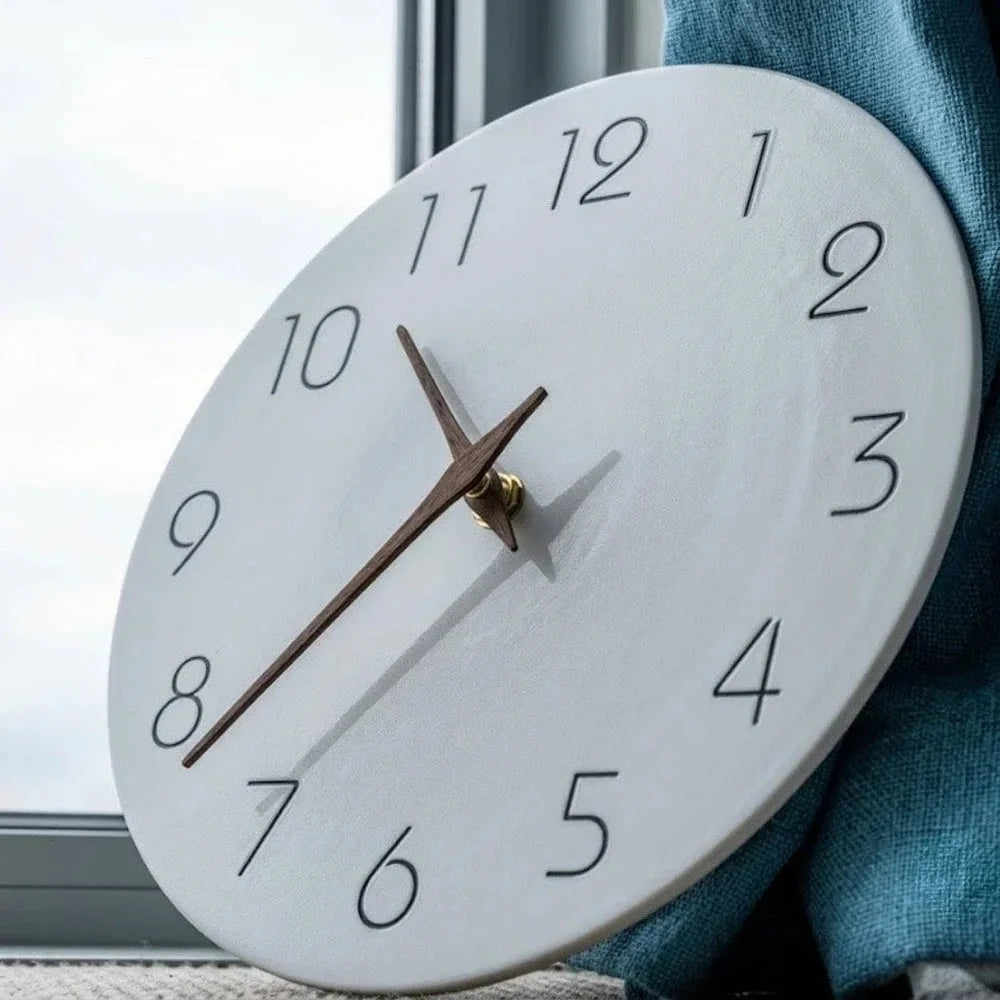 The white clock leaning against a window beside a teal curtain, showing the brass center collar