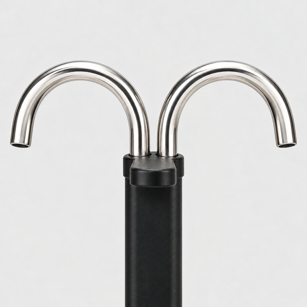 Close-up of the two curved stainless steel spouts rising from the black column of a mini moka pot