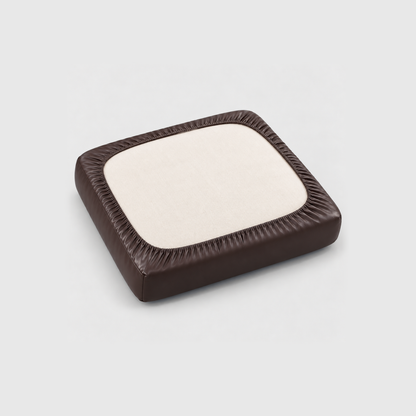 Underside of a seat cushion in a brown PU leather cover, the elastic hem gathered all around the cream cushion fabric