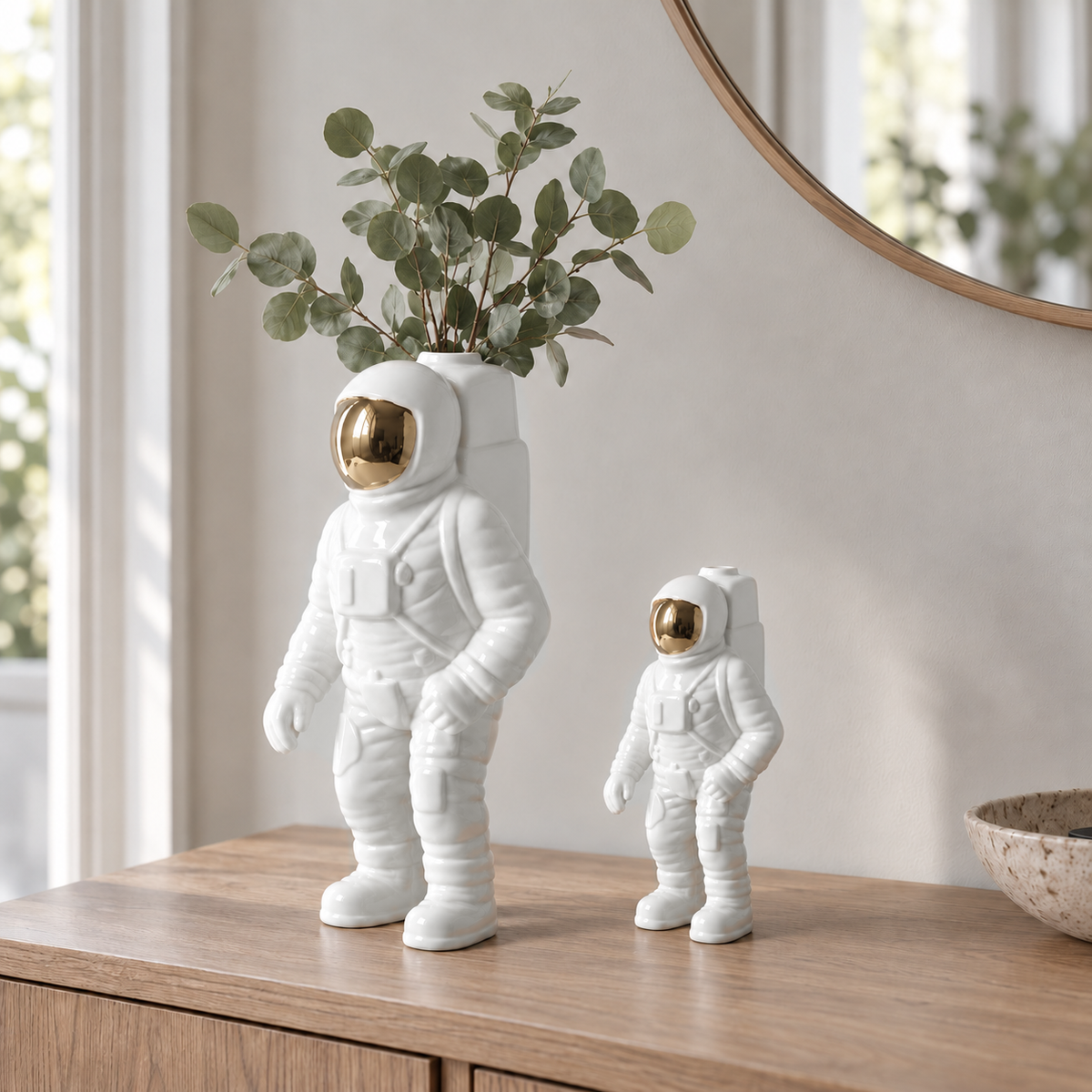 A large and a small white astronaut vase side by side on an oak console table, the large one holding eucalyptus