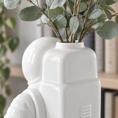Close view of eucalyptus stems standing in the round opening on top of the white astronaut vase's backpack