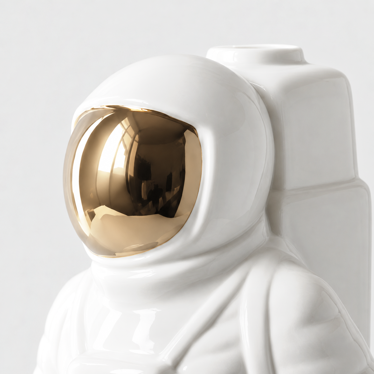 Close view of the white astronaut vase's helmet with its mirror gold visor