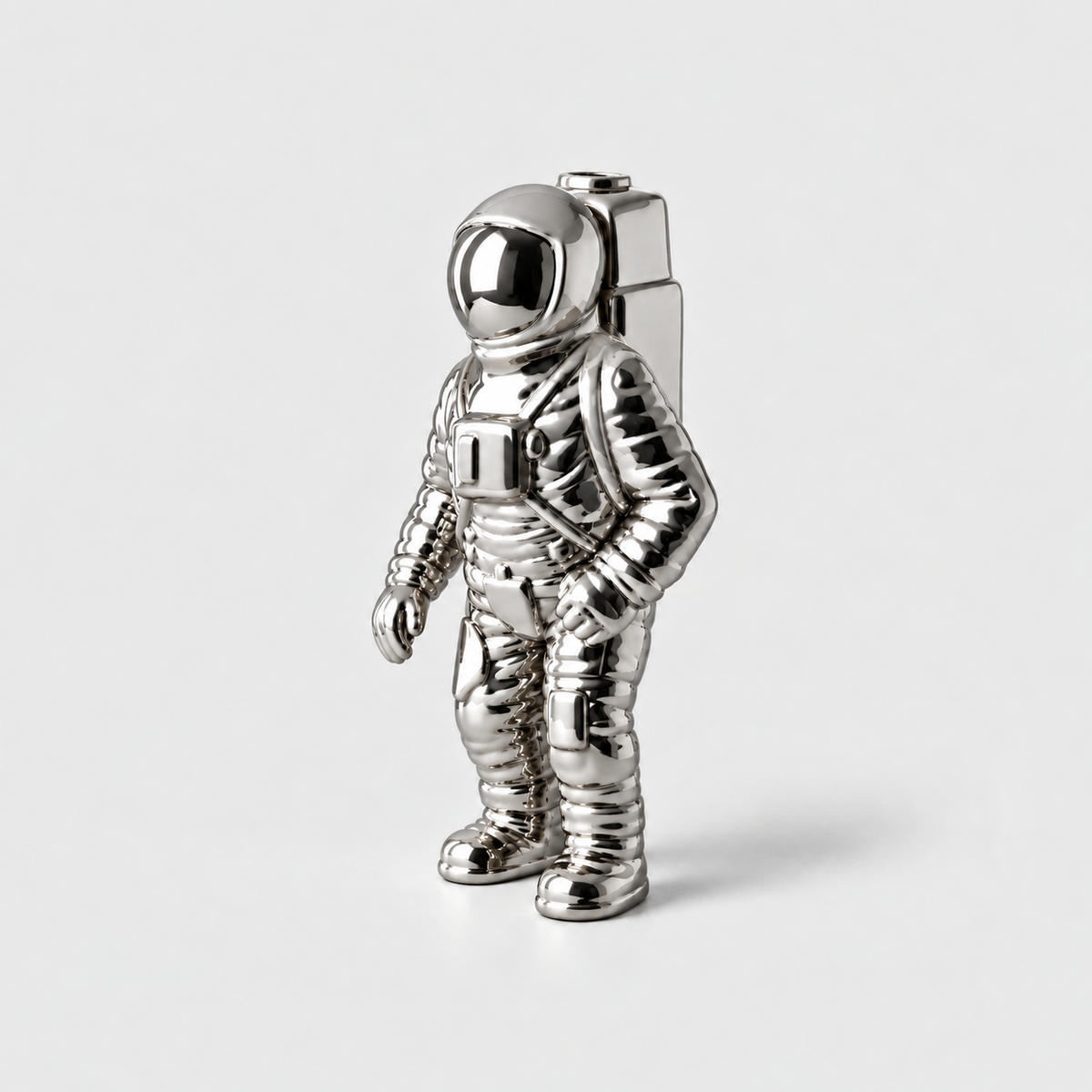 A mirror silver ceramic astronaut vase with a backpack opening, standing on a light gray background