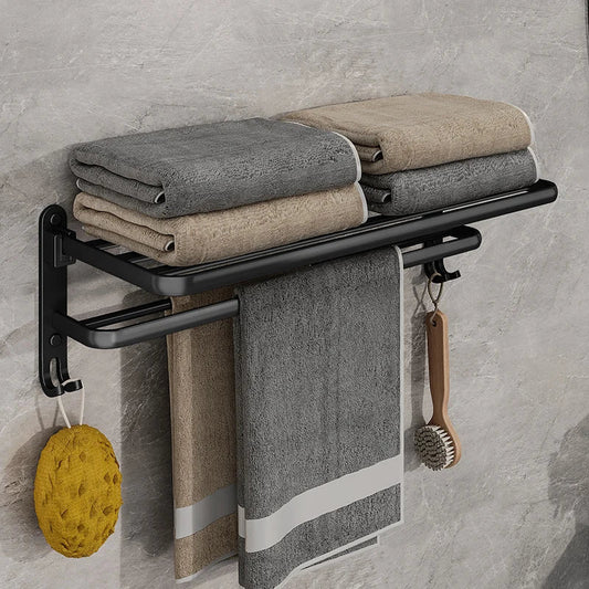 Matte black towel rack seen from the front with two stacks of folded towels on top and a towel hanging from the bar