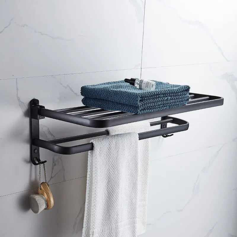 Black aluminum towel rack on a white marble wall with folded teal towels on the shelf and a white towel on the bar