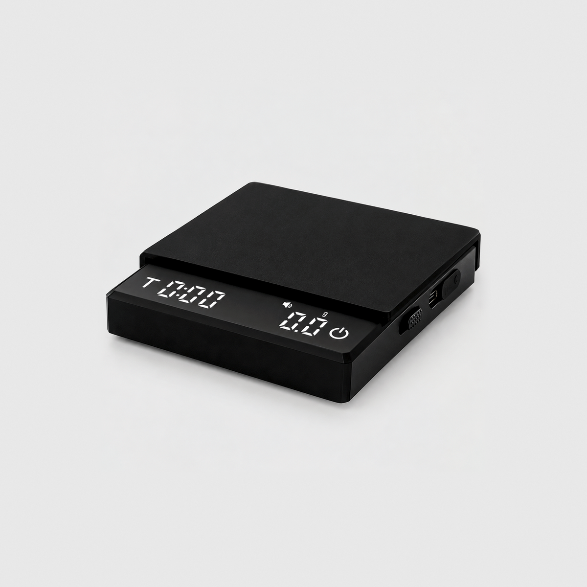 Black coffee scale with its silicone mat on top and the display lit showing the timer and 0.0 grams, on a light gray studio background