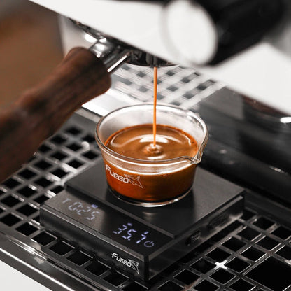 Black coffee scale on an espresso machine drip tray as a shot pours into a glass cup, the display showing time and weight