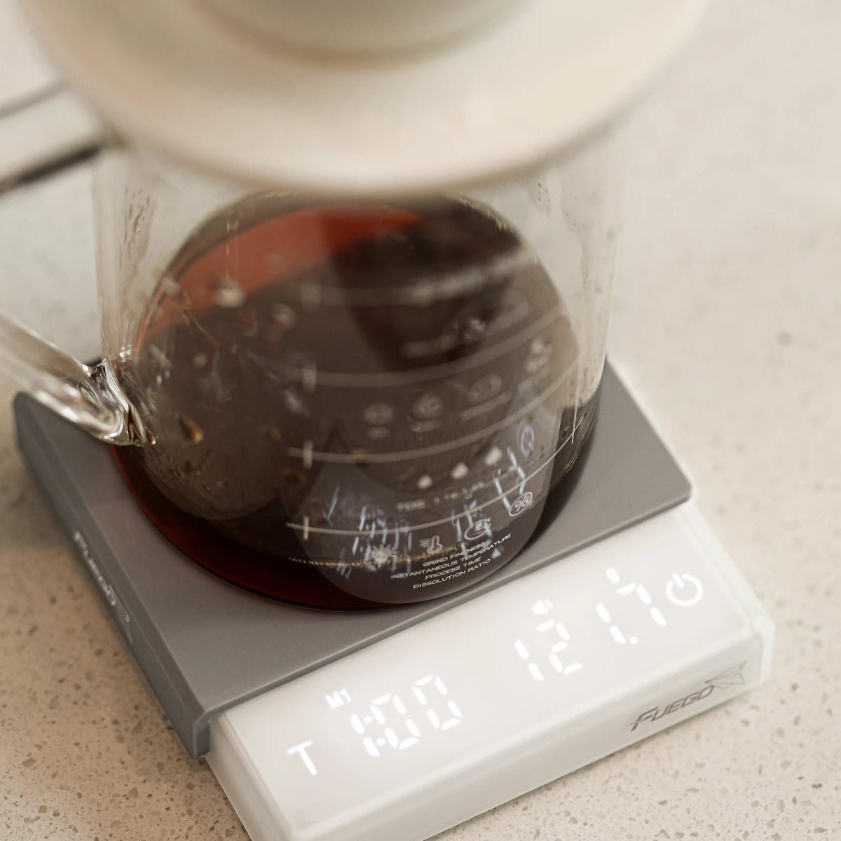 White coffee scale seen from above under a glass server and dripper, the display showing pour-over mode, time and weight