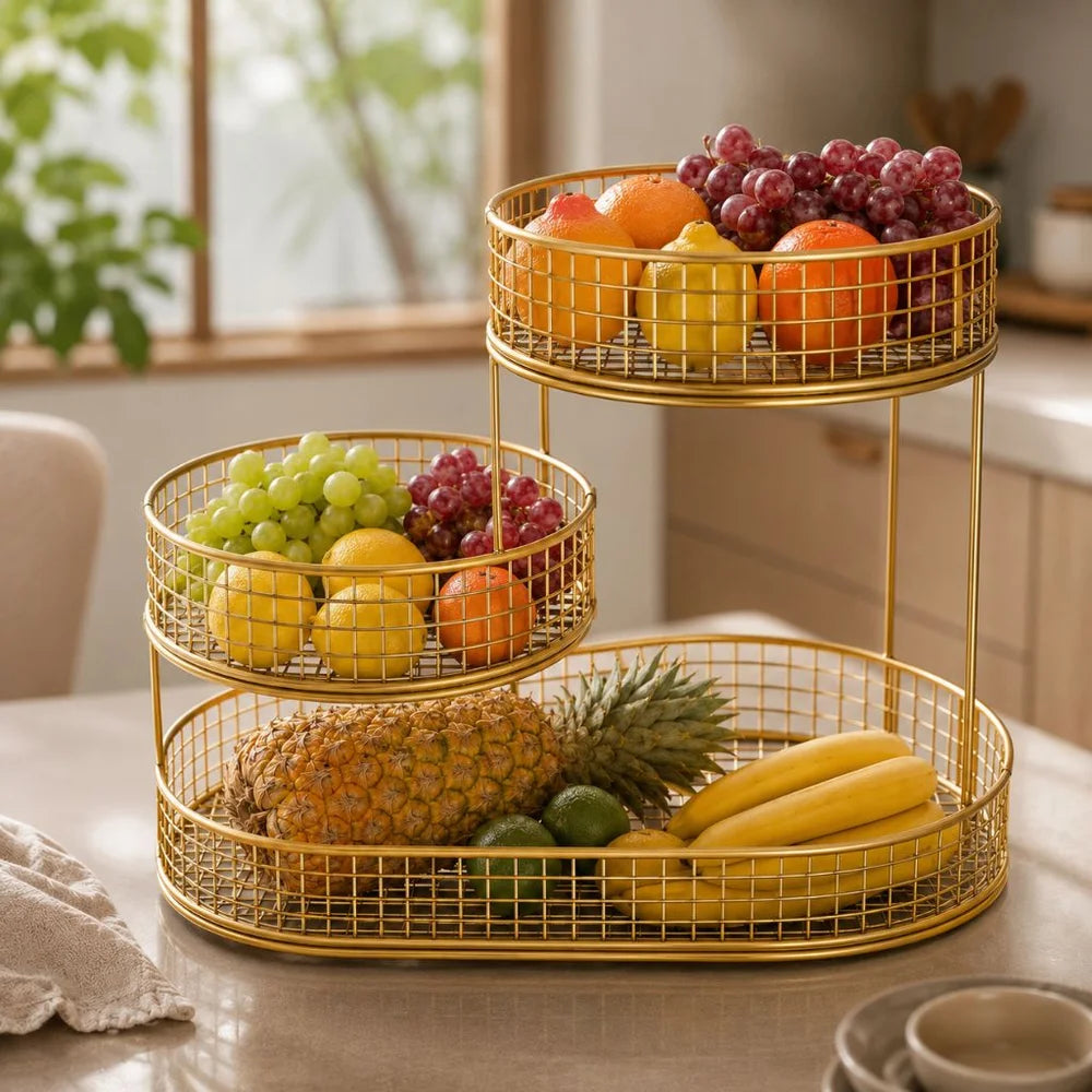 Gold three tier wire fruit basket stand filled with fruit on a kitchen counter in sunlight