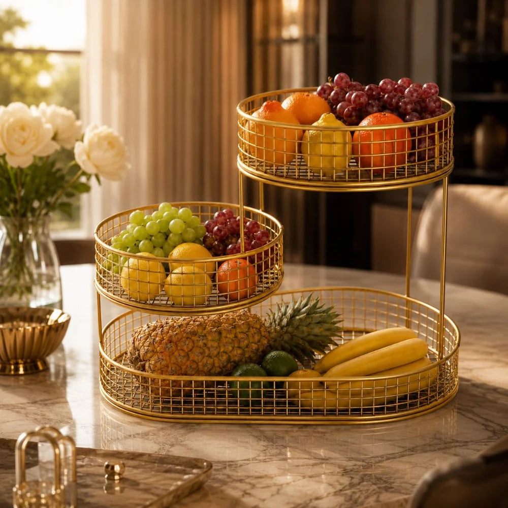 Gold three tier fruit stand on a marble kitchen island beside a vase of white roses