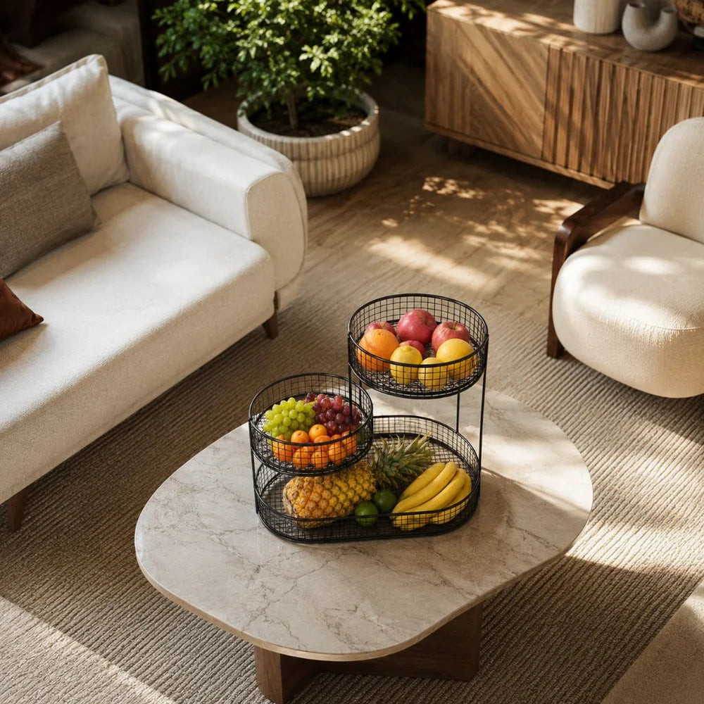 Black three tier fruit stand on a round stone coffee table in a living room, seen from above