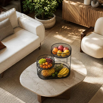 Black three tier fruit stand on a round stone coffee table in a living room, seen from above