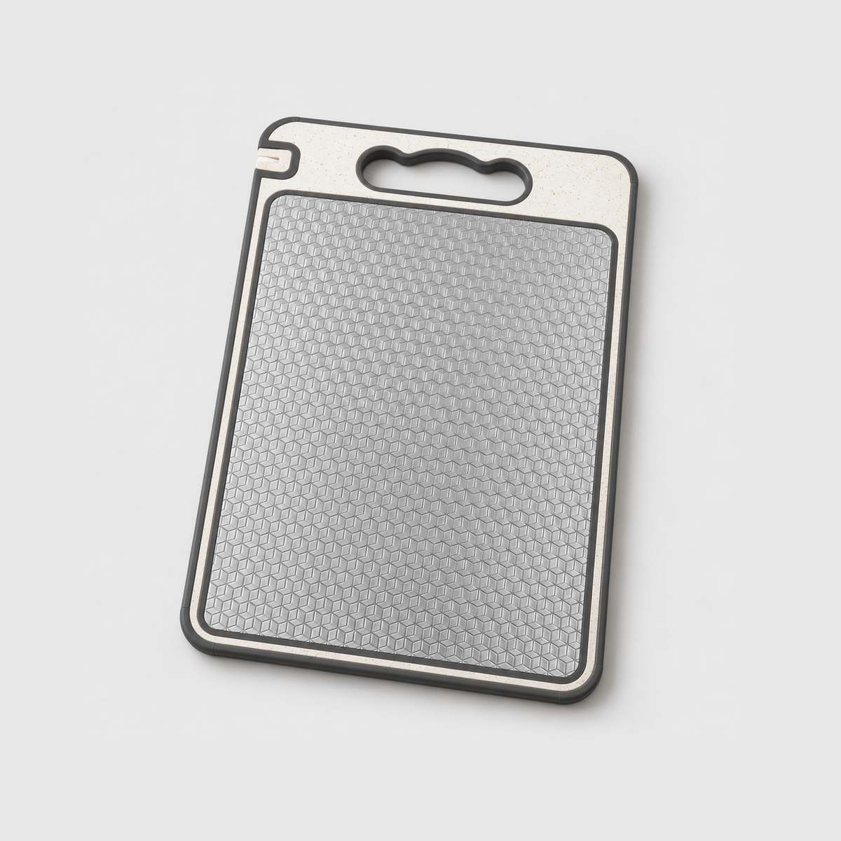 Double sided cutting board with a textured stainless steel side, a cream handle end and a gray silicone edge, on a light gray background