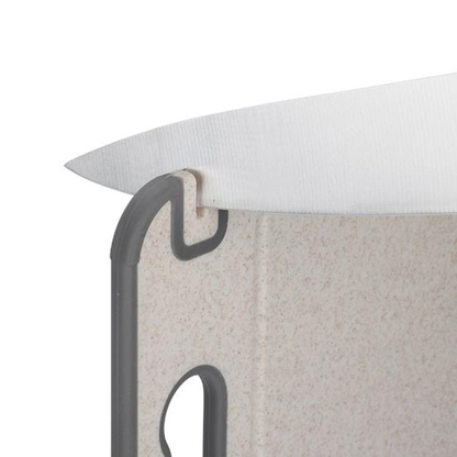 A kitchen knife with its edge in the built-in sharpener slot at the corner of the cutting board