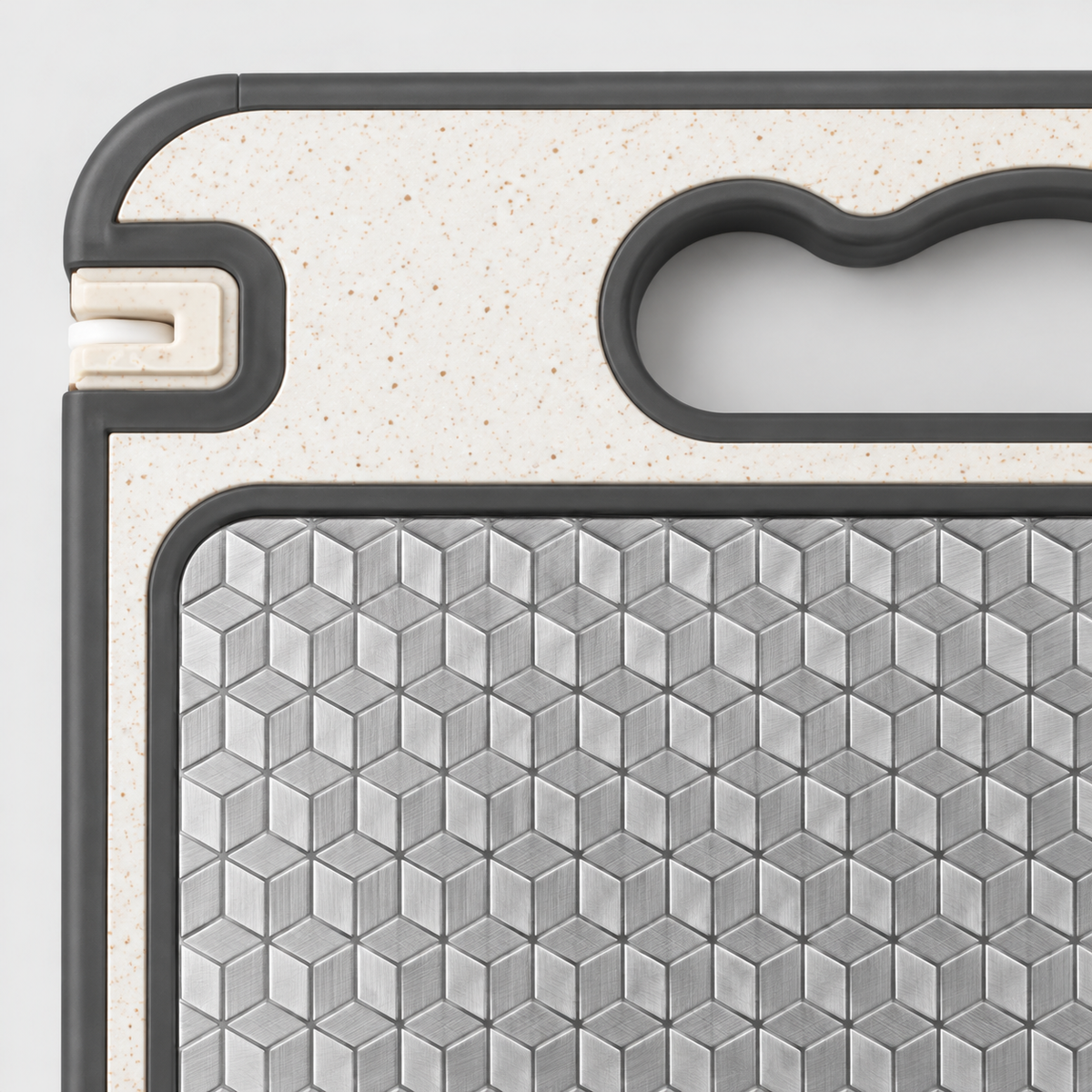 Close-up of the raised cube pattern on the stainless steel side meeting the cream handle end and the gray silicone edge