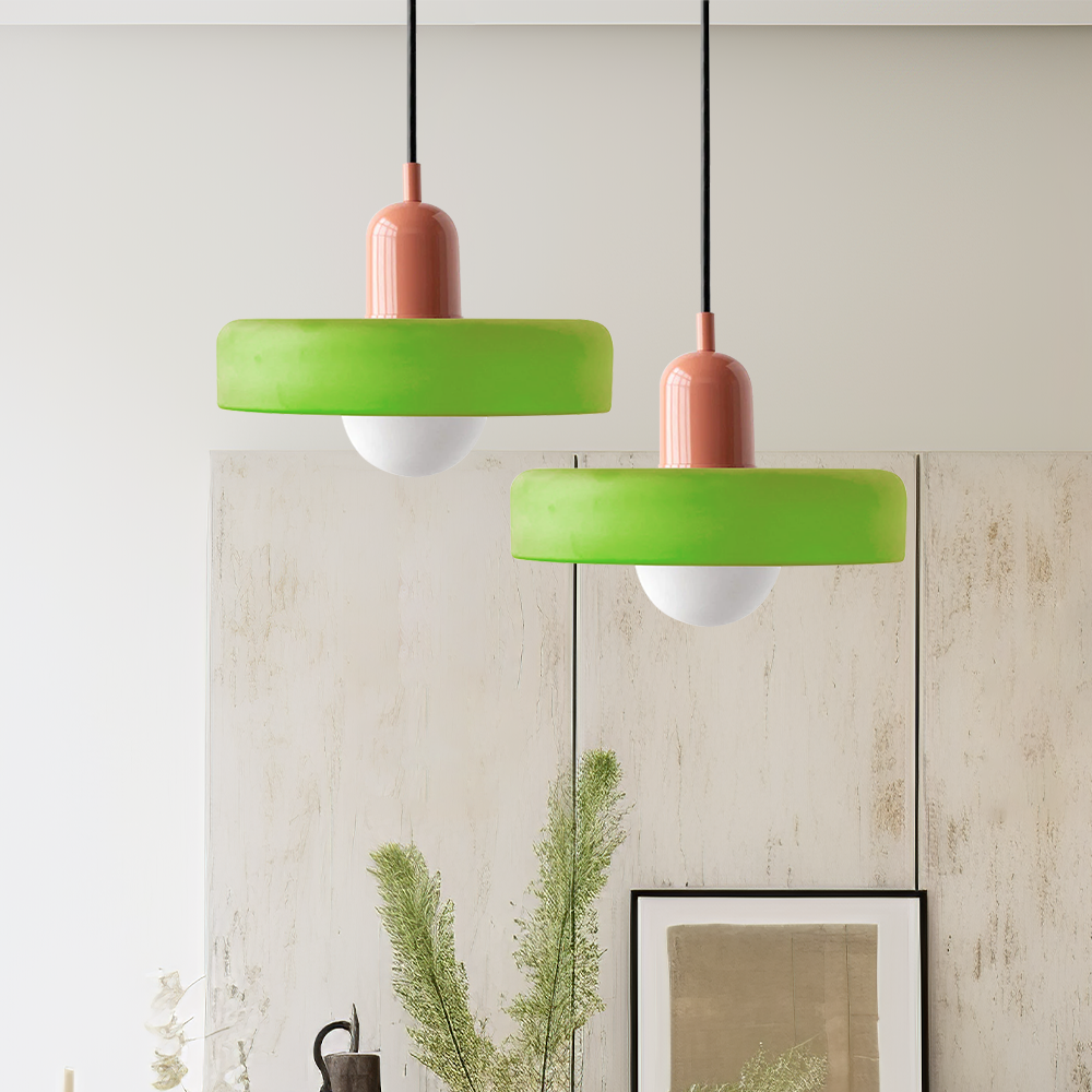 Two green glass ring pendants on pink bodies hanging at different heights in a bright room