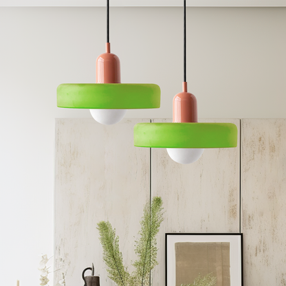 Two green glass ring pendants on pink bodies hanging at different heights in a bright room