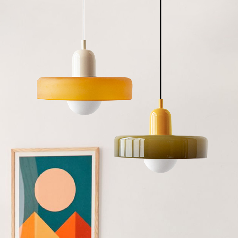 An amber shade on a beige body and an olive shade on a yellow body hanging beside a geometric art print