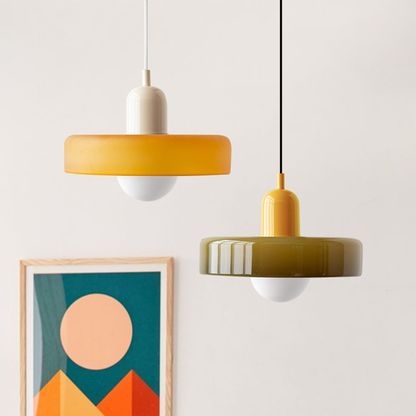 An amber shade on a beige body and an olive shade on a yellow body hanging beside a geometric art print