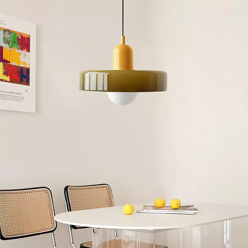 Olive glass pendant with a yellow body over a white round table with lemons