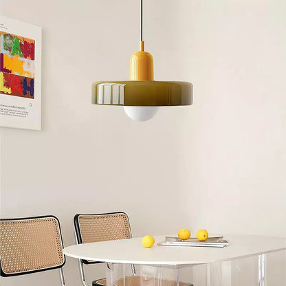 Olive glass pendant with a yellow body over a white round table with lemons