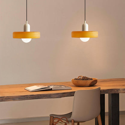 Two amber glass pendants with beige bodies hanging over a live edge wooden desk