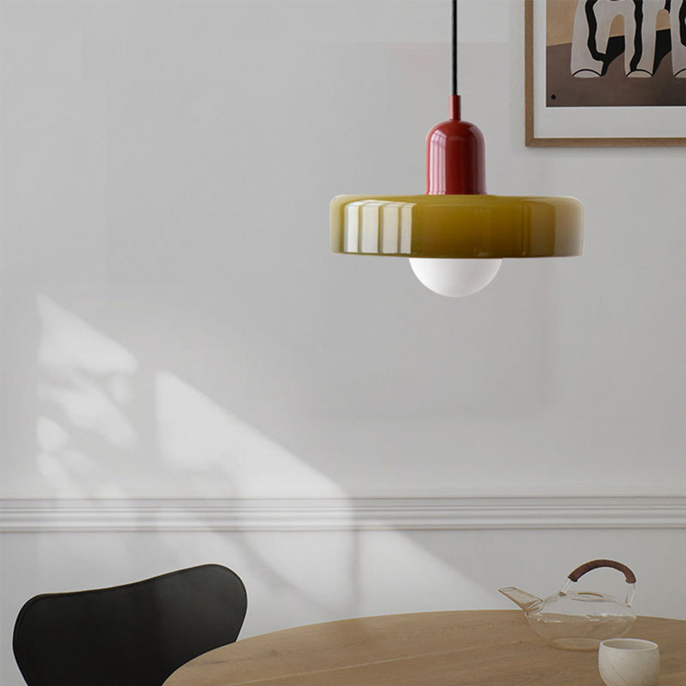 Olive glass pendant with a burgundy body above a round dining table and a black chair