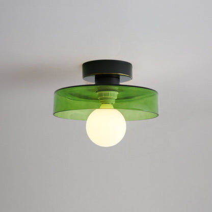 Ceiling light with a tinted green glass disc shade on a black base, lit from below by a frosted globe