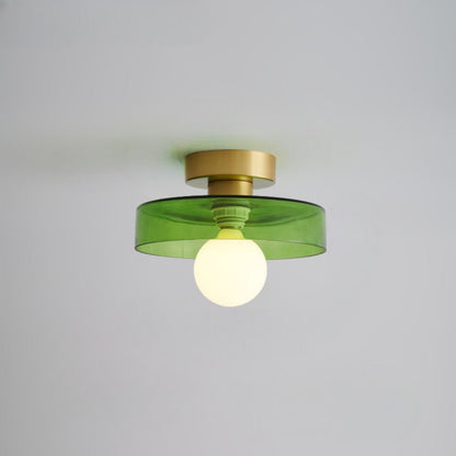 Ceiling light with a tinted green glass disc shade on a gold-toned base, lit from below by a frosted globe