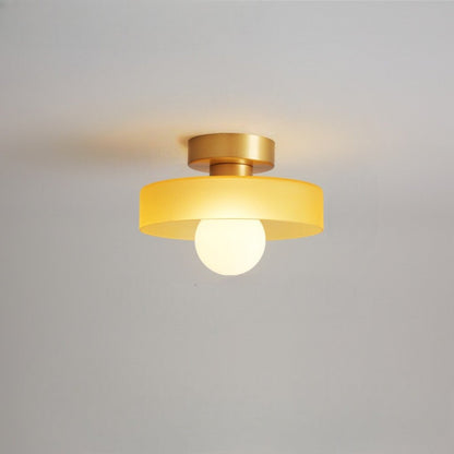 Ceiling light with a yellow glass disc shade on a gold-toned base, a frosted globe glowing beneath it