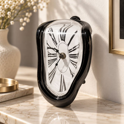 A glossy black melting clock standing on a marble shelf beside a vase of dried flowers