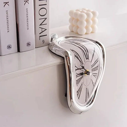 A silver melting clock draped over the edge of a white shelf beside a row of books