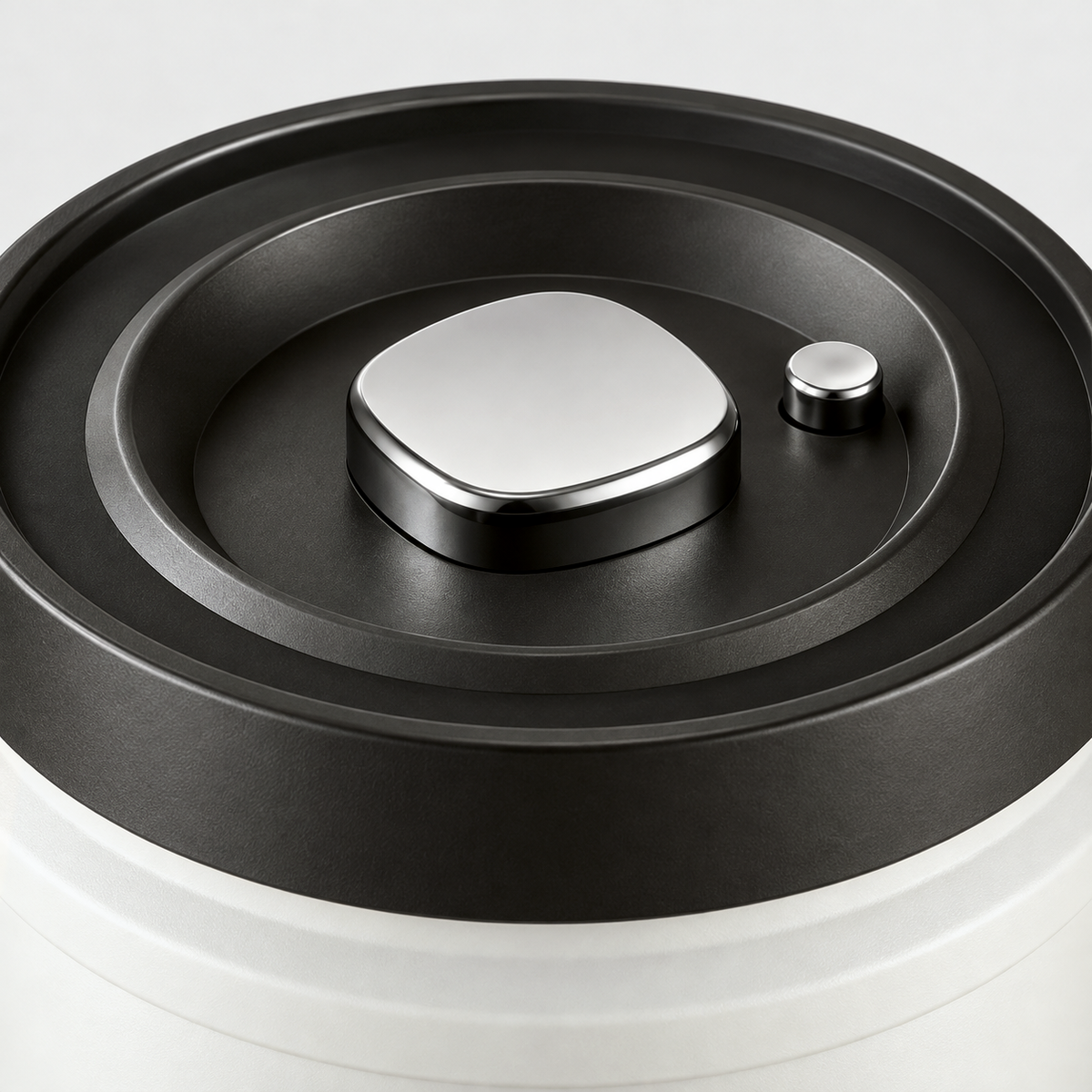 Close-up of the silver push button vacuum pump and the small air release button on the black canister lid