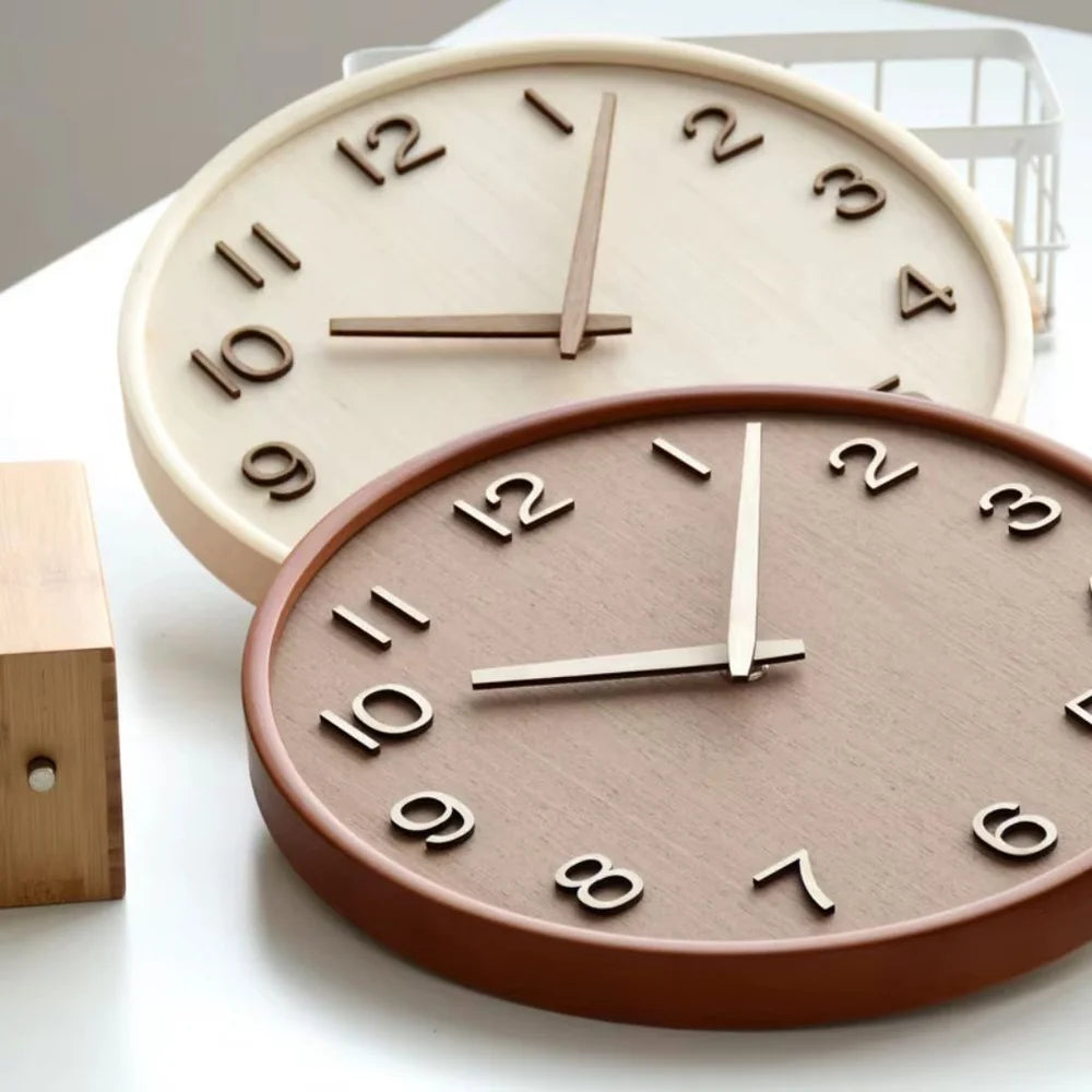 Natural and brown wooden wall clocks lying on a white table, showing the raised cut-out numbers and the rounded rims