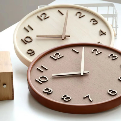 Natural and brown wooden wall clocks lying on a white table, showing the raised cut-out numbers and the rounded rims