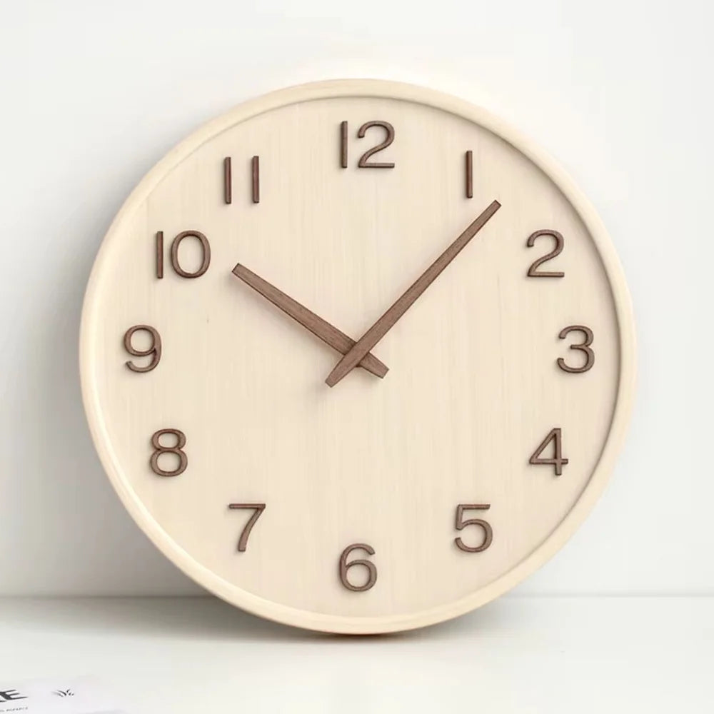Natural wood wall clock with walnut numbers and hands propped upright against a white wall