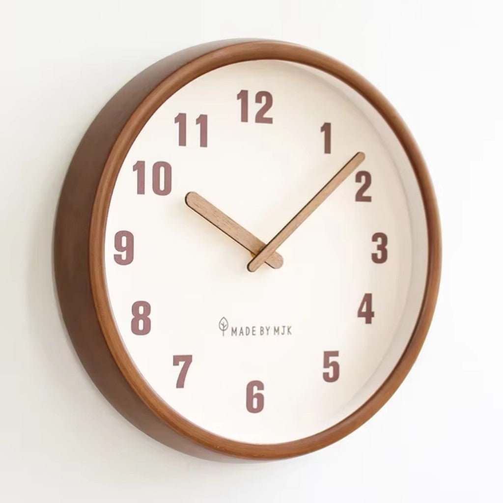 Round wall clock with a walnut-brown wood frame, a white face with large plum-brown numbers and two wooden hands, seen at an angle on a white wall