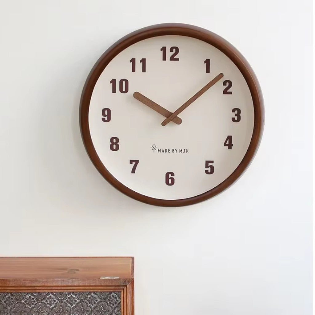 The White wall clock hung on a pale wall above a wooden cabinet