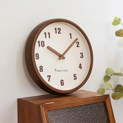 The White clock standing on top of a wooden cabinet with textured glass, eucalyptus leaves to one side