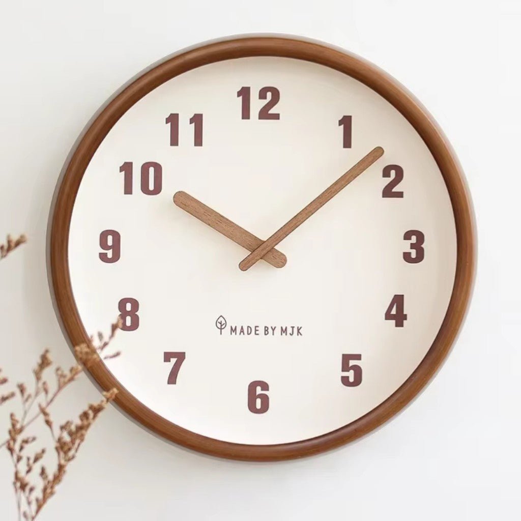 Front view of the White clock showing the wood frame, the large plum-brown numbers and the wooden hands, with dried flowers in the corner