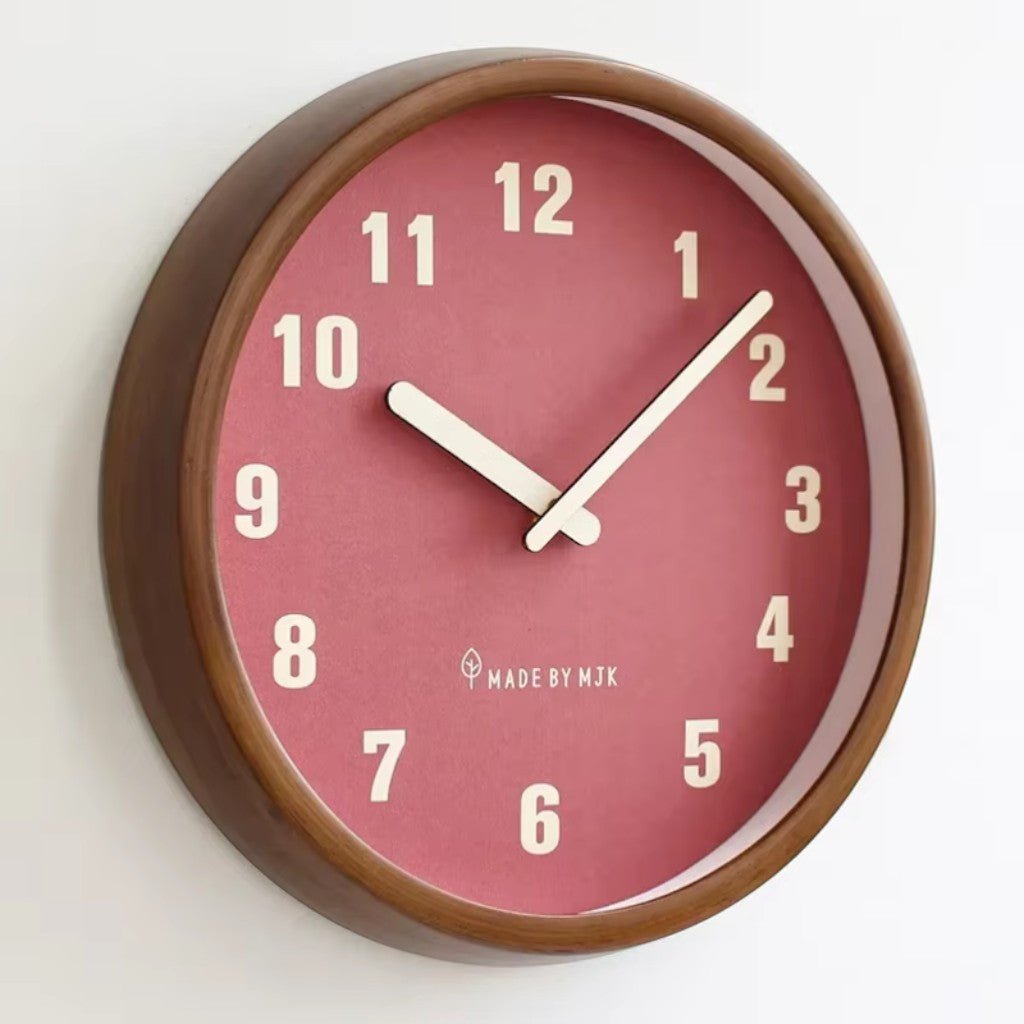 Round wall clock with a walnut-brown wood frame, a red face with cream numbers and cream hands, seen at an angle on a white wall