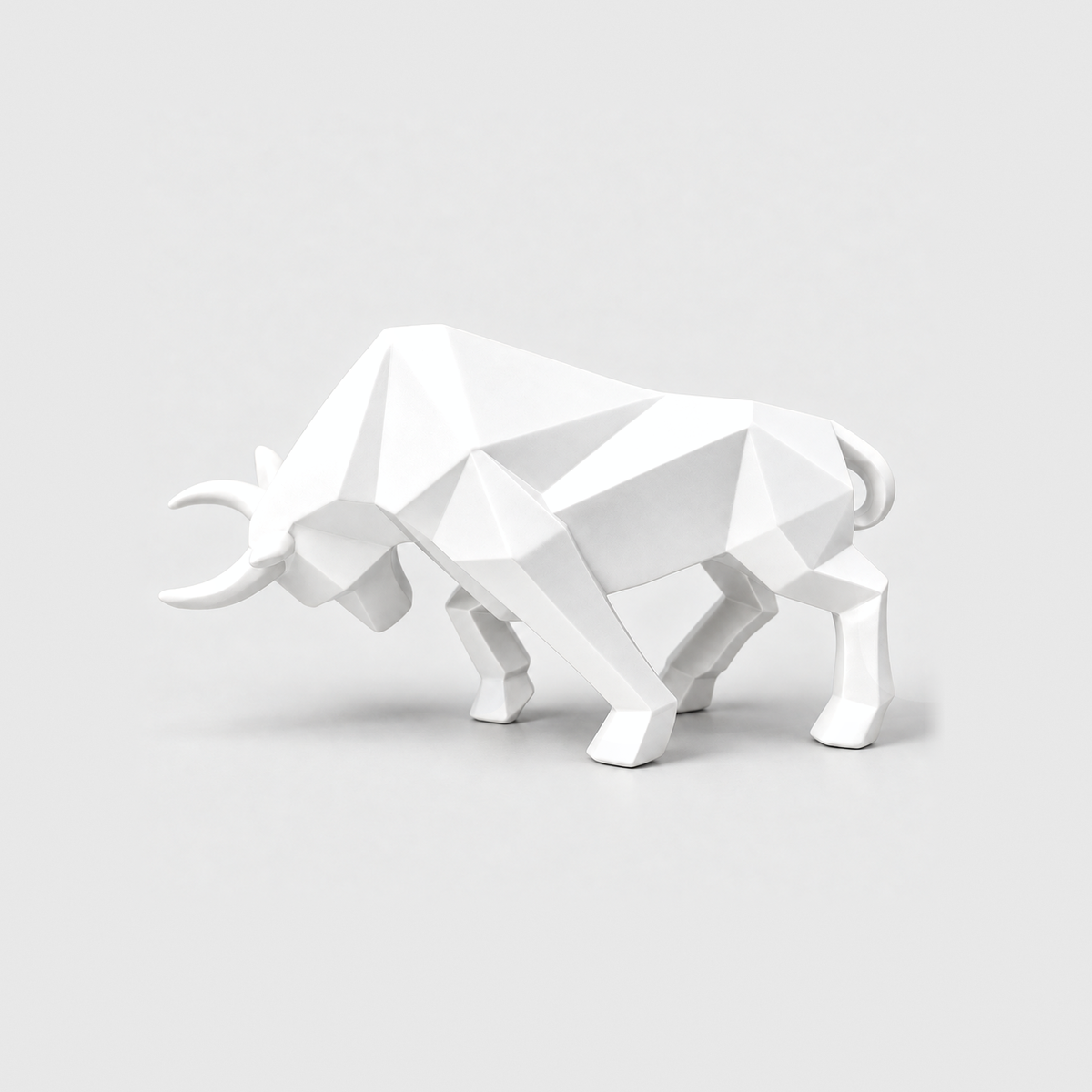 A white geometric bull sculpture with faceted planes, standing on a light gray background