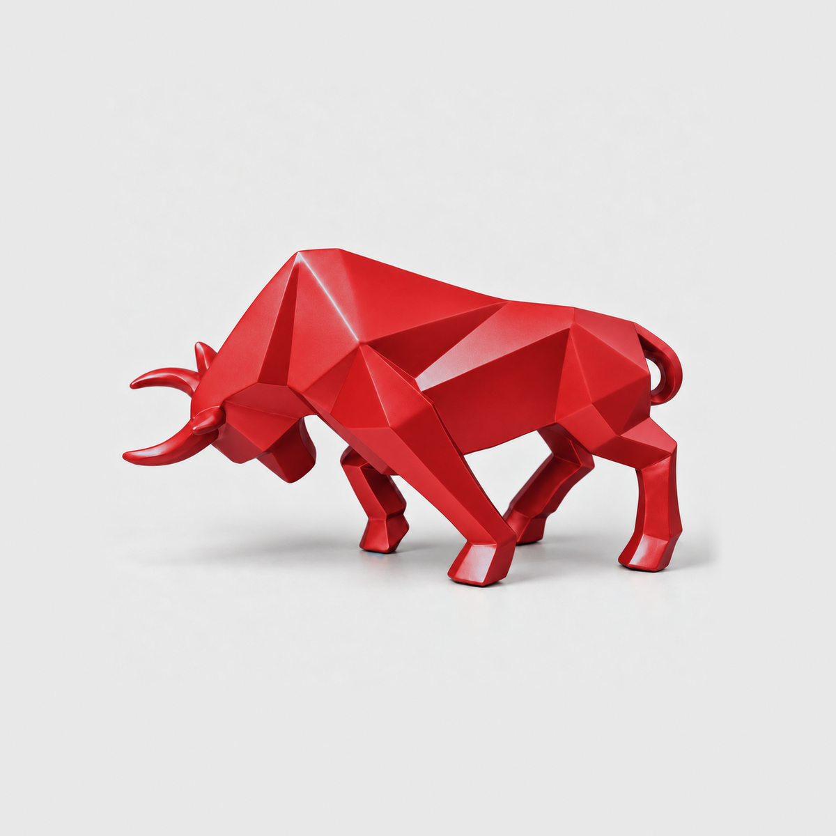 A red geometric bull sculpture with faceted planes, standing on a light gray background