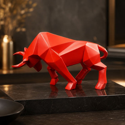 A red geometric bull sculpture on a black marble block, with soft gold lights behind it