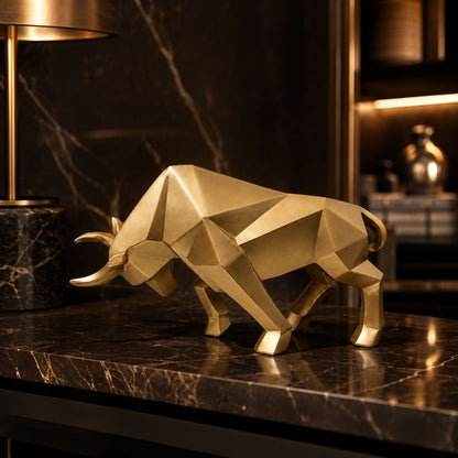 A gold faceted bull sculpture on a dark marble shelf beside a lamp, lit by warm shelf lights