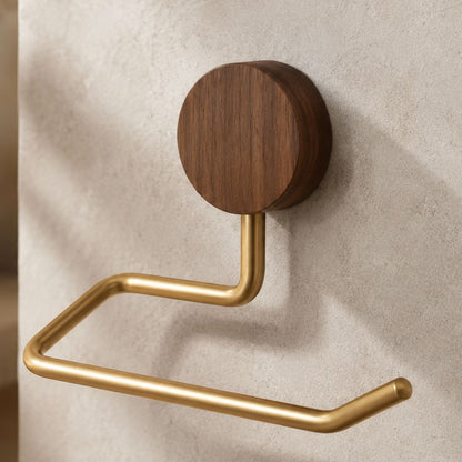 Walnut and gold toilet paper holder with an open-ended arm on a pale stone wall