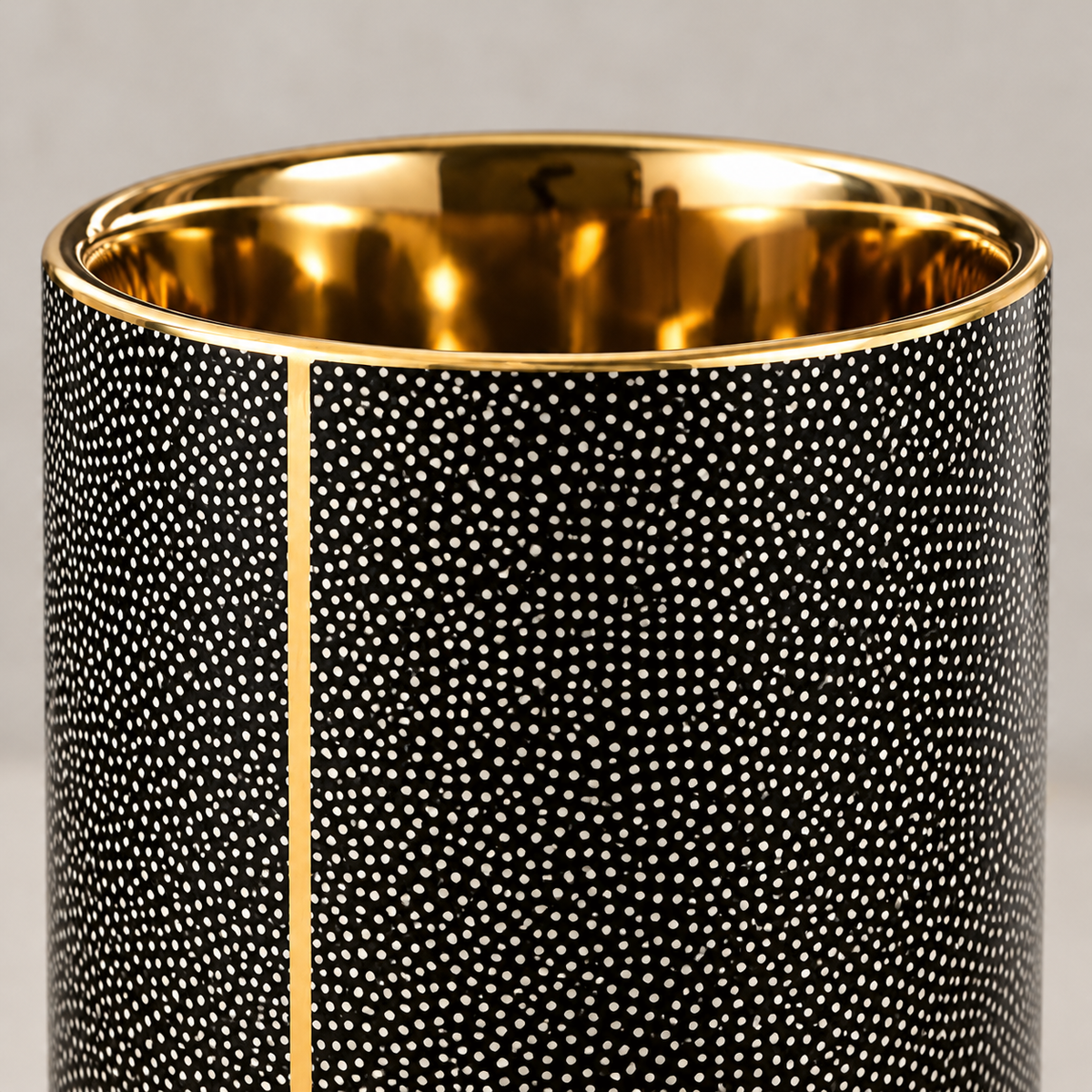 Close-up of the black tumbler rim: tiny cream dots in swirling rows, a thin gold-coated rim line and seam, and the gold-coated inside