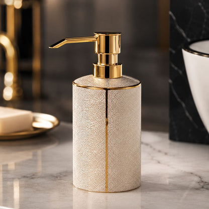 White ceramic soap dispenser with a gold-tone pump and a gold-coated seam line